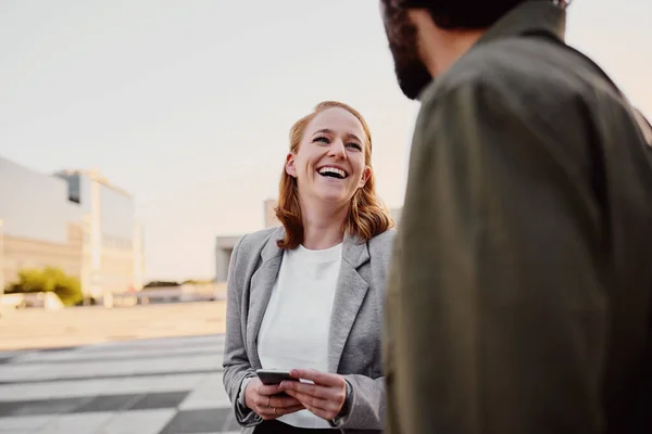 Portret van succesvolle en lachende zakenvrouw in gesprek met mannelijke partner op straat — Stockfoto
