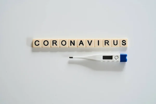 Coronavirus spelt with tiles and thermometer on white background — 스톡 사진