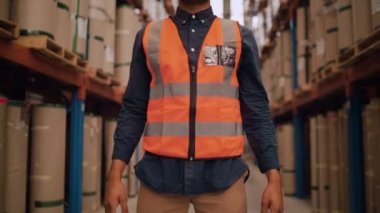 Afro-Amerikalı genç bir depo görevlisinin güvenlik şapkalı portresini üretim deposunun önünde çekelim.