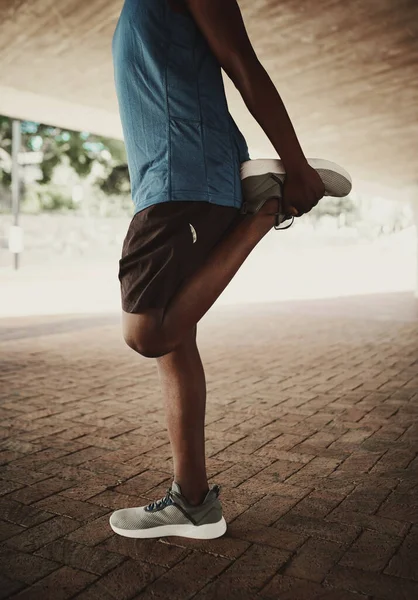 Sección baja de un estilo de vida saludable hombre afroamericano estirando las piernas antes de correr en la calle de la ciudad —  Fotos de Stock