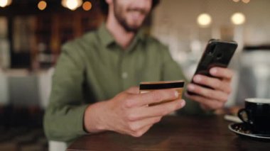 İnternet üzerinden alışveriş yapan ve kafede dinlenirken banka kartıyla alışveriş yapan bir adamın ellerine odaklanın - çevrimiçi alışverişler