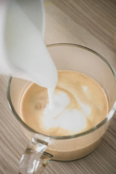 The milk foam is pouring into the coffee. — Stock Photo, Image