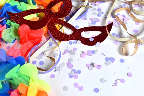 Červená karnevalová maska v barevných konfetách a stuhách — Stock fotografie