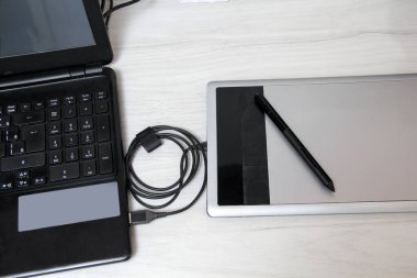 Ofis masasında dizüstü bilgisayarlı fare altlığı grafikleri, tablet ofis gereçleri, masadaki not defterinde metin için yer var.
