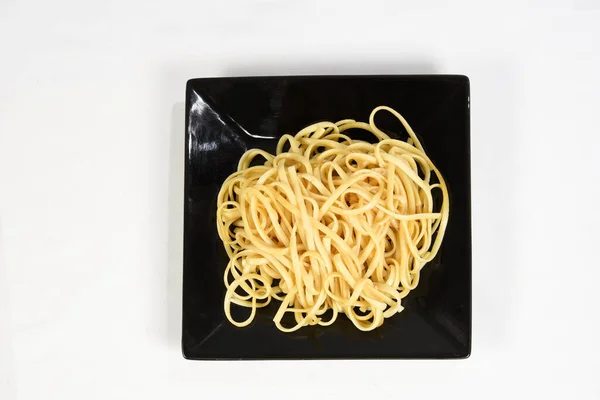 Plade Frisk Spaghetti Med Olivenolie Den Sorte Plade Isoleret Hvid - Stock-foto