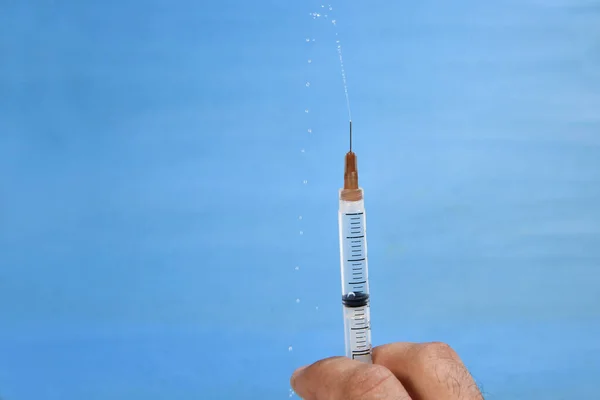 medical syringe with needle, used for vaccine against diseases and viruses isolated over blue background with space for text.