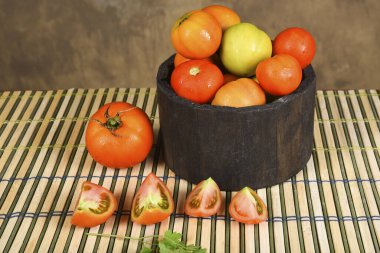 Bir kasede çeşitli sulu ve lezzetli domatesler. Arka planda bulanık domates parçaları var.