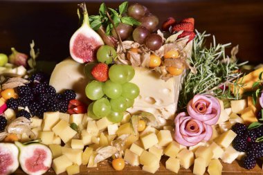 Üzüm, incir, çilek, peynir, jambon, ahududu ve baharatlı lezzetli porsiyon kırsal ahşap tahtada bulanık servis edilir.