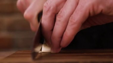 Tahtada sarımsak doğrayan bir adam. Karanfil. Dilimleniyor