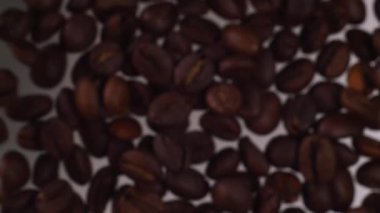 Kahve çekirdekleri yavaş çekimde uçuyor. Kahve çekirdekleri beyaz arka bahçeye düşer. Yavaş kahve.