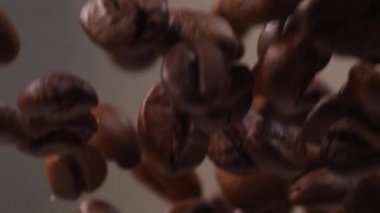 Kahve çekirdekleri yavaş çekimde uçuyor. Kahve çekirdekleri beyaz arka bahçeye düşer. Yavaş kahve.