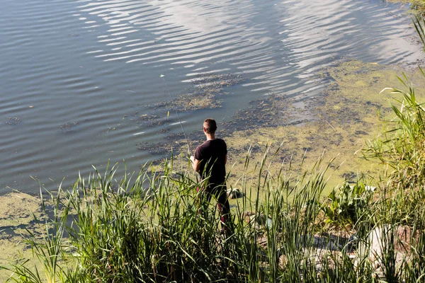Ένας Νεαρός Ψαράς Στην Όχθη Ενός Βρώμικου Κατάφυτου Ποταμού Προσπαθεί — Φωτογραφία Αρχείου