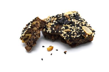 Ev yapımı ekmek ve fırın brownisi, üzerinde yer fıstığı, üzümler, güneş çekirdekleri beyaz ve siyah susam tohumları olan pasta ısırılmış ve kırıntılar.. 