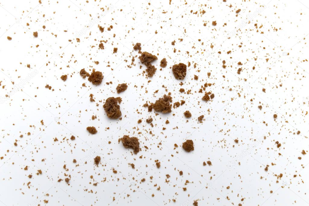 Scattered crumbs of chocolate chip butter cookies on white background.