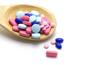 Tahta kaşıkta çeşitli ilaç hapları var. Beyaz arkaplanda ve boşluğu kopyala.