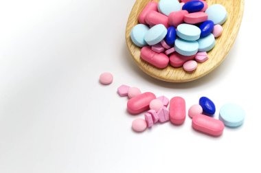 Tahta kaşıkta çeşitli ilaç hapları var. Beyaz arkaplanda ve boşluğu kopyala.