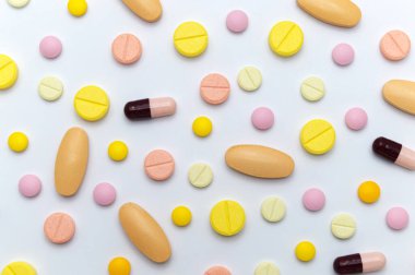 Beyaz arka planda tedavi ve sağlık hizmetleri için farklı renkli ilaçlar veya ilaç hapları. Üst görünüm.