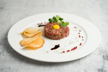 Çiğ etli tart, ince çıtır kıtır ekmek ve balzamik sosla servis edilir.