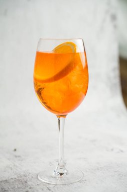 Aperol Spritz kokteyli, açık arkaplanda buz ve turuncu bir bardakta.