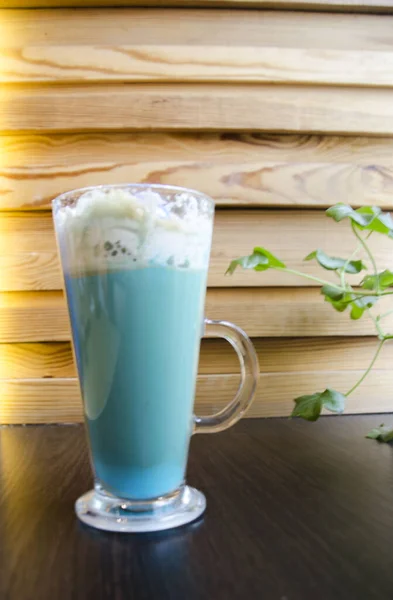 Ahşap arka planda kremalı mavi latte.