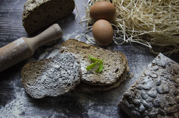 Koyu arkaplanda yumurta ve un dilimlenmiş kahverengi ekmek.