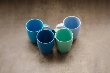 Gri arka planda dört farklı renkte çay fincanı.