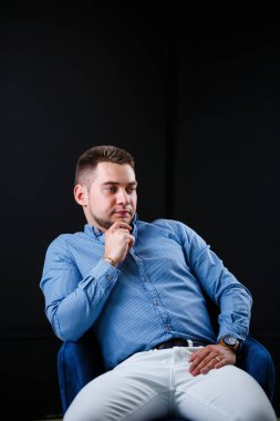 Siyah arka planda beyaz pantolon ve mavi gömlekli iş adamı.