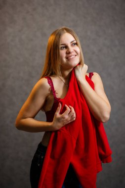 Kız gri arka planda kırmızı bir kazak deniyor.