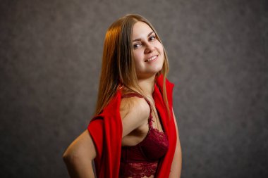 Kız gri arka planda kırmızı bir kazak deniyor.