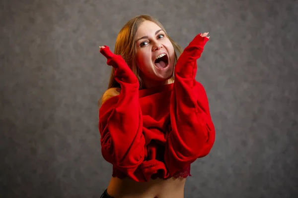 Lány Felpróbál Egy Piros Pulóvert Szürke Alapon — Stock Fotó