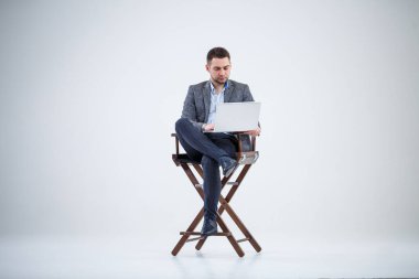 Erkek öğretmen iş adamı bir sandalyede oturmuş belgeleri inceliyor. O, dizüstü bilgisayar ekranına bakıyor. Yeni iş projesi.