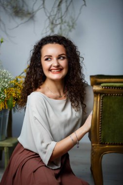 Kıvırcık elbiseli güzel bir manken. Güzel bir şekilde poz veriyor. Çiçeklerle baharın başlangıcı