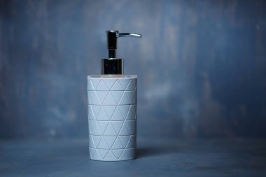 Gri bir masada metal kapaklı gri sabun makinesi.