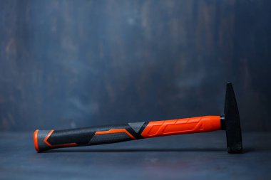 Gri arka planda siyah turuncu küçük bir çekiç..