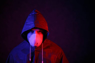 Coronavirus. Maskeli ve kimyasal korumalı kırmızı ve mavi ışık altında bir adam. Virüse karşı savaş