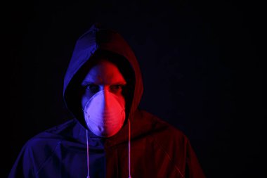 Maskeli ve kimyasal korumalı kırmızı ve mavi ışık altında bir adam. Virüse karşı savaş. COVID-19