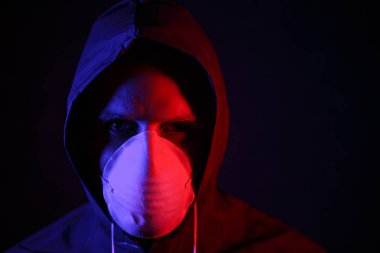 Coronavirus. Maskeli ve kimyasal korumalı kırmızı ve mavi ışık altında bir adam. Virüse karşı savaş
