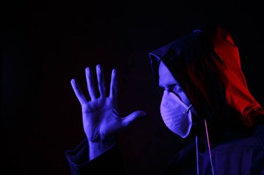 Maskeli ve kimyasal korumalı kırmızı ve mavi ışık altında bir adam. Virüse karşı savaş. COVID-19