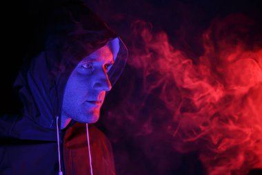 Koruyucu giysili bir adam duman üfledi. Cadılar Bayramı imajı. Virüs koruması. Renkli ışıklarla aydınlatılmış