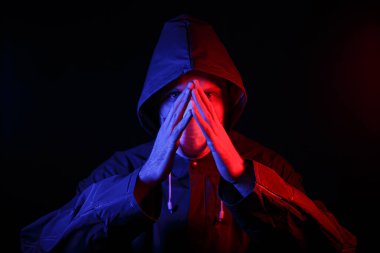 Koruyucu kauçuk giysili ve beyaz tıbbi maskeli bir adam. Virüs koruması. Kırmızı ve maviyle aydınlatılmış.