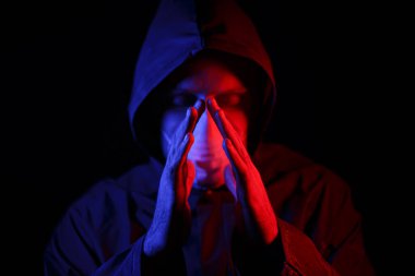 Koruyucu kauçuk giysili ve beyaz tıbbi maskeli bir adam. Virüs koruması. Kırmızı ve maviyle aydınlatılmış.