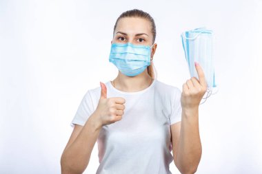 Koruyucu tıbbi maskeli bir kız elinde tutarak solunum yolunu virüsten korur..