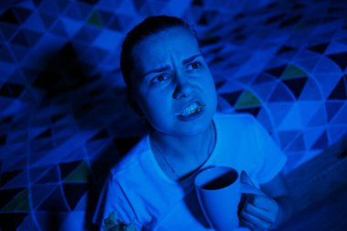 Genç, güzel bir kız televizyon izliyor, kruvasan yiyor ve çay içiyor. Evde dinlen.