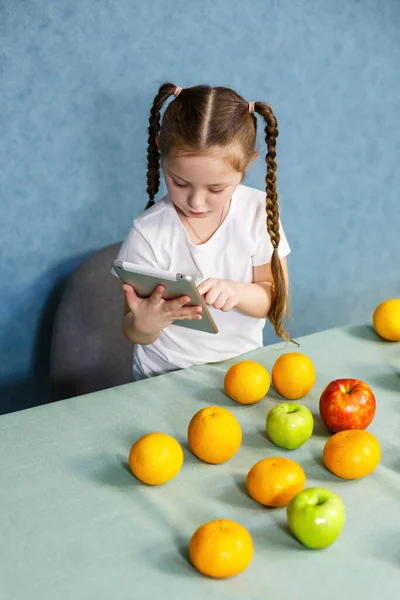 Liten Flicka Vit Shirt Håller Tablett Händerna Och Studerar Frukterna — Stockfoto