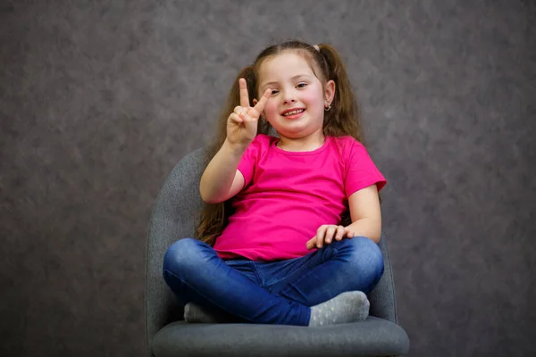 Menina Uma Camiseta Rosa Está Sentado Uma Cadeira Cinza Foto — Fotografia de Stock