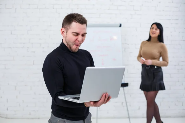 Businessman man stands with a laptop while a woman writes a business plan on a white board. Stand on a white background. A girl learns new business rules with a girl student