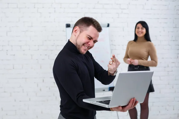 Businessman man stands with a laptop while a woman writes a business plan on a white board. Stand on a white background. A girl learns new business rules with a girl student