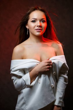 Güzel kız beyaz ceketinin düğmelerini çözer ve güzel gülümser.