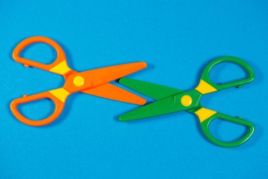 Renkli bir arkaplanda kağıt figürleri kesmek için çocuk plastik makası