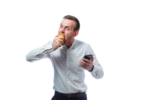 白人男性商人拿着黑色手机 拿着红黄苹果 他穿着一件衬衫 感情用事因白人背景而被隔离 — 图库照片